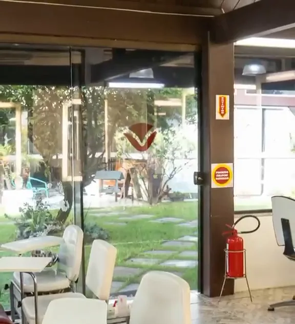 Porta de vidro do Le Visage com o logo e o jardim ao fundo