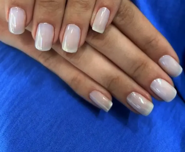 Mãos com unhas esmaltadas em tom nude claro